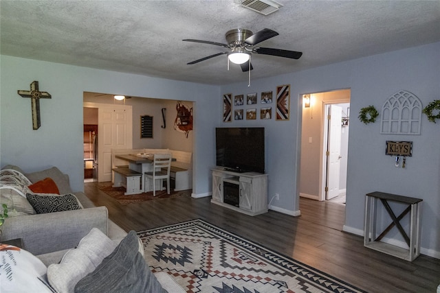 living room with ceiling fan, dark hardwood / wood-style flooring, and a textured ceiling