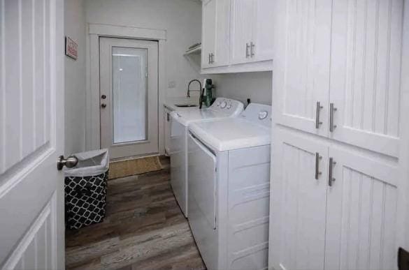 clothes washing area featuring washer and dryer, dark hardwood / wood-style floors, cabinets, and sink