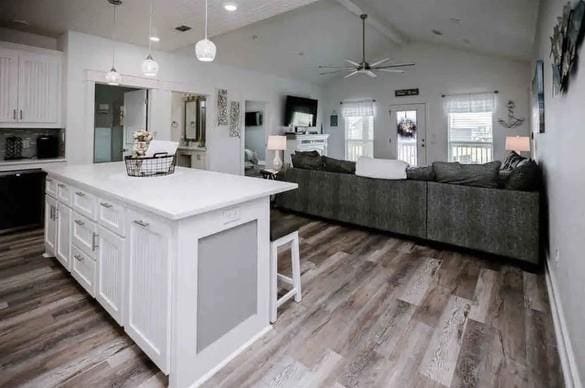 kitchen with white cabinets, vaulted ceiling with beams, ceiling fan, a kitchen island, and dark hardwood / wood-style flooring