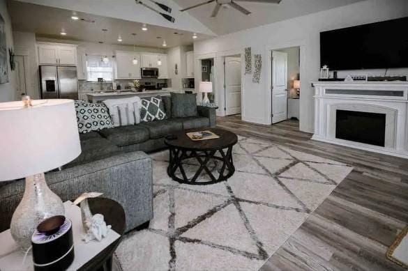 living room featuring hardwood / wood-style flooring, ceiling fan, and lofted ceiling