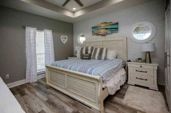 bedroom with a tray ceiling, ceiling fan, and dark hardwood / wood-style floors