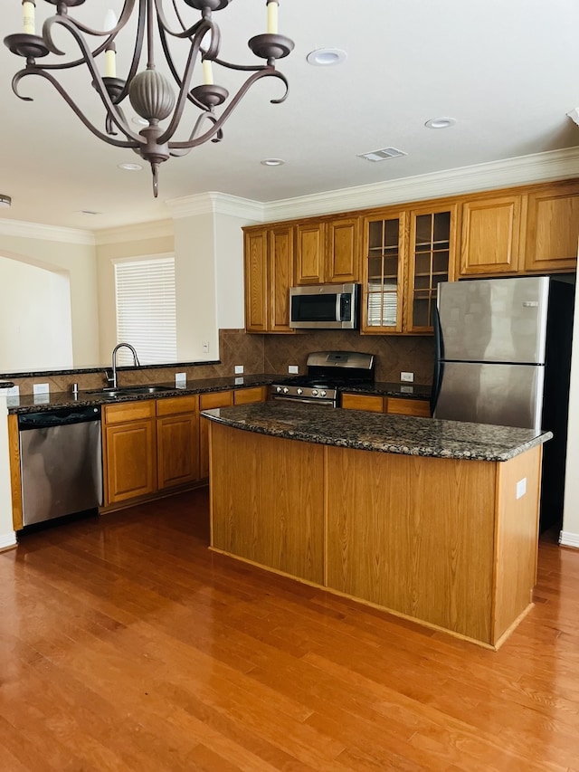 kitchen featuring appliances with stainless steel finishes, dark stone counters, sink, pendant lighting, and a chandelier