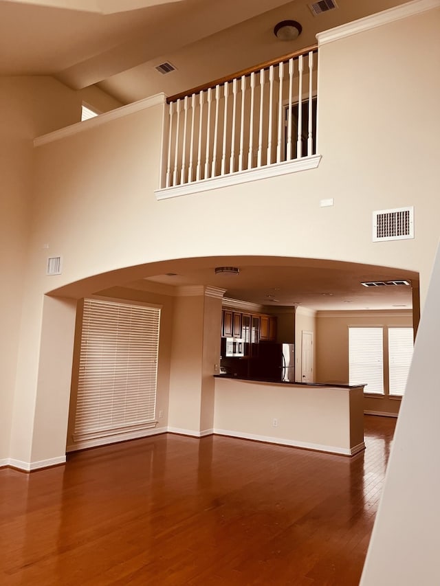 unfurnished living room with dark hardwood / wood-style flooring, lofted ceiling, and crown molding