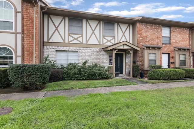 view of front of home with brick siding, a front lawn, and stucco siding