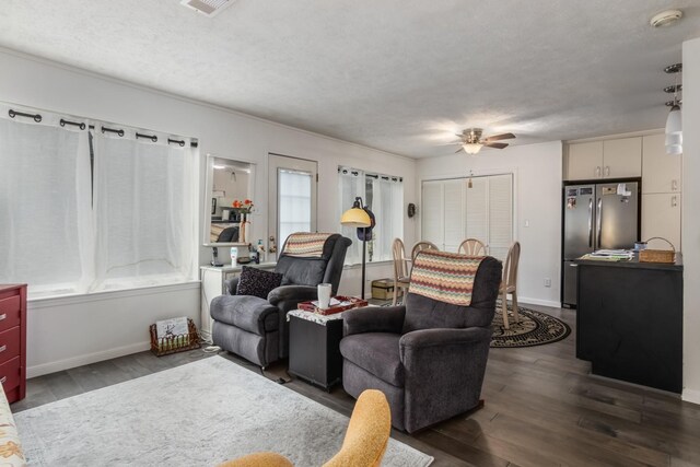 living room with ceiling fan, plenty of natural light, dark hardwood / wood-style floors, and a textured ceiling