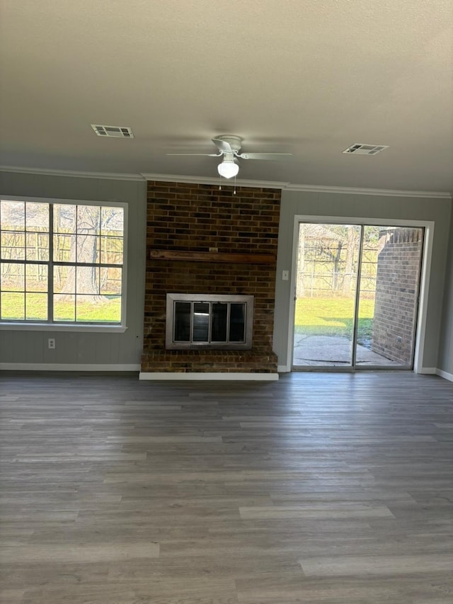 unfurnished living room with ceiling fan, a fireplace, wood-type flooring, and ornamental molding