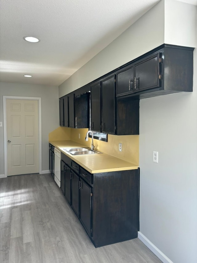 kitchen with a textured ceiling, light wood-type flooring, white dishwasher, and sink