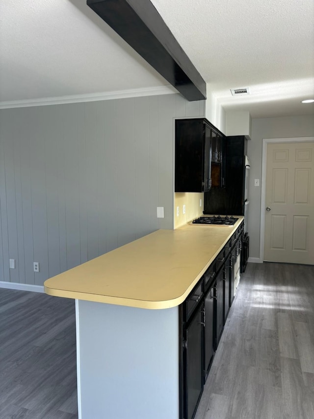 kitchen featuring kitchen peninsula, a textured ceiling, gas stovetop, dark hardwood / wood-style floors, and a breakfast bar area