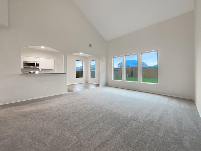 unfurnished living room with carpet floors and high vaulted ceiling