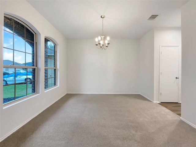 carpeted empty room featuring a notable chandelier