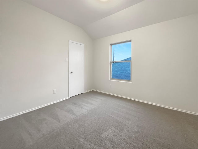 carpeted empty room with vaulted ceiling