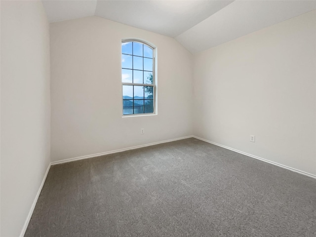 unfurnished room featuring dark colored carpet and lofted ceiling