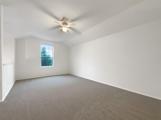 empty room with dark carpet, vaulted ceiling, and ceiling fan