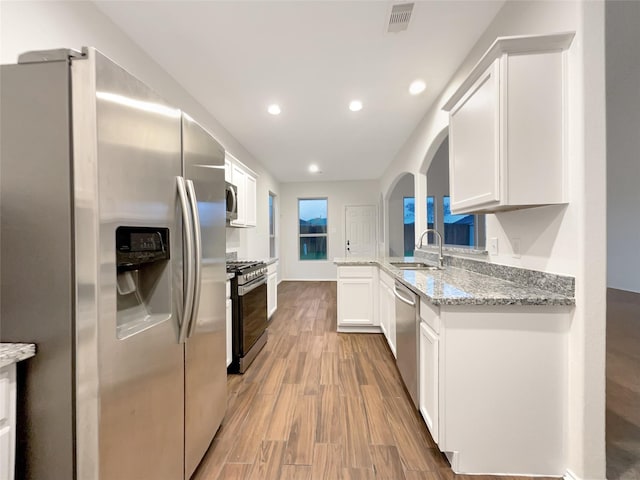 kitchen featuring white cabinets, sink, light stone countertops, light hardwood / wood-style floors, and stainless steel appliances