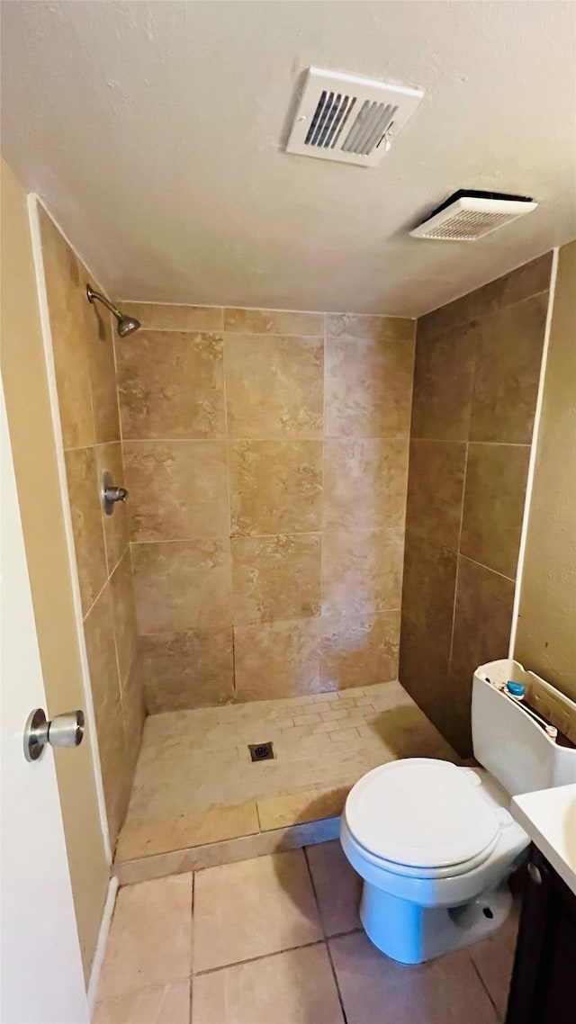 bathroom featuring tiled shower, tile patterned floors, vanity, and toilet