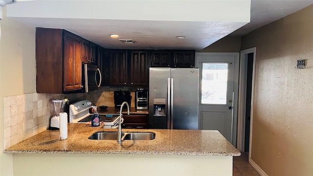 kitchen with kitchen peninsula, appliances with stainless steel finishes, decorative backsplash, and sink