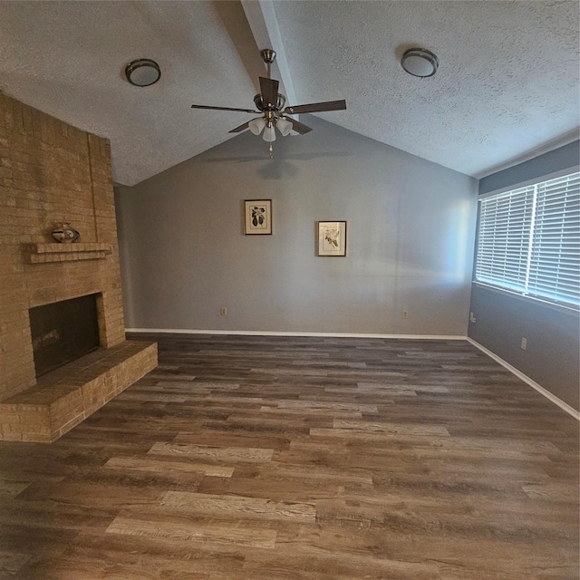 unfurnished living room with ceiling fan, a brick fireplace, dark hardwood / wood-style floors, a textured ceiling, and vaulted ceiling