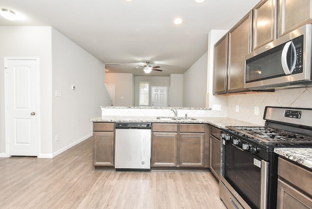 kitchen featuring ceiling fan, light stone counters, sink, and appliances with stainless steel finishes