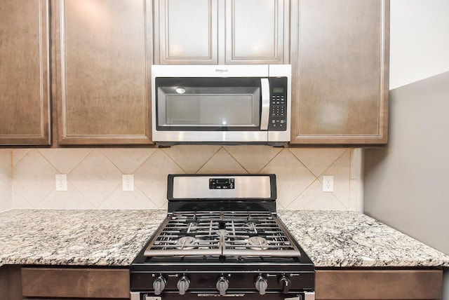 kitchen featuring decorative backsplash, light stone countertops, and appliances with stainless steel finishes