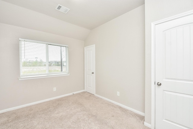 empty room with light colored carpet and vaulted ceiling