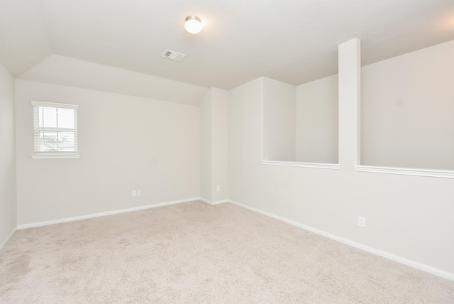 carpeted empty room with vaulted ceiling