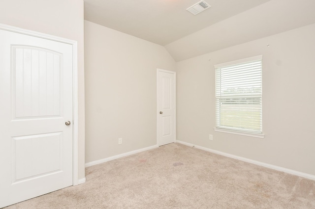 carpeted empty room with lofted ceiling