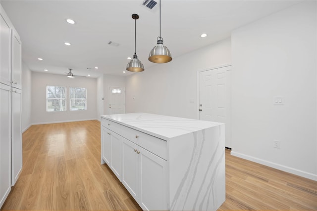 kitchen with light stone countertops, white cabinetry, hanging light fixtures, and a center island