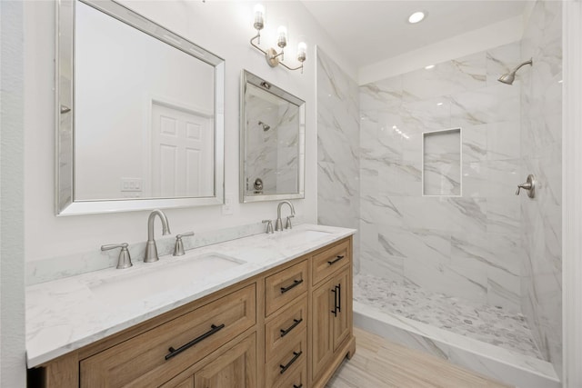 bathroom with a tile shower and vanity