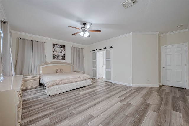 unfurnished bedroom with ceiling fan, a barn door, crown molding, and light hardwood / wood-style flooring