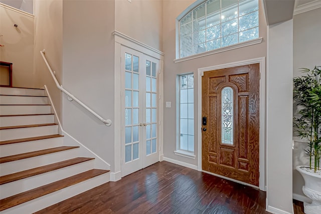 foyer entrance featuring french doors, a towering ceiling, and dark wood-type flooring