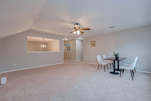 dining area with vaulted ceiling, light colored carpet, and ceiling fan with notable chandelier