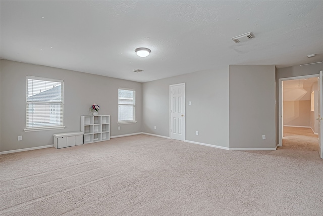 spare room with a textured ceiling and light colored carpet