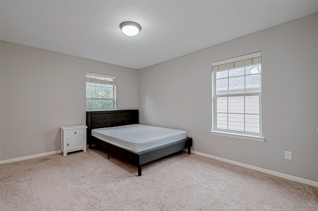 bedroom featuring light colored carpet and a textured ceiling