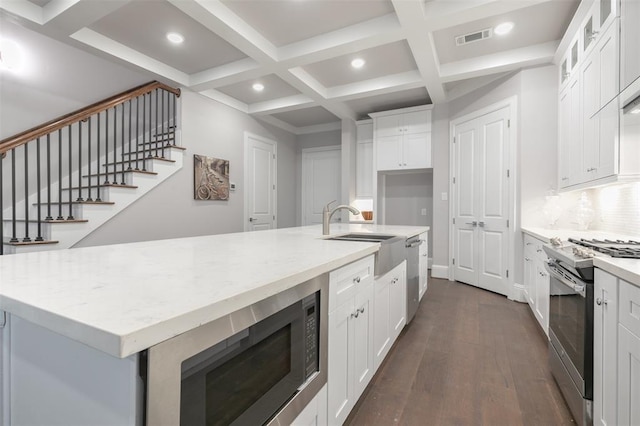 kitchen with white cabinets, stainless steel appliances, a kitchen island with sink, and sink