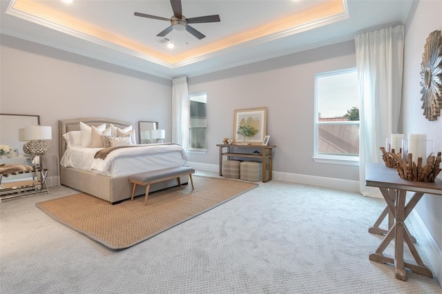 bedroom featuring a tray ceiling, ceiling fan, crown molding, and carpet