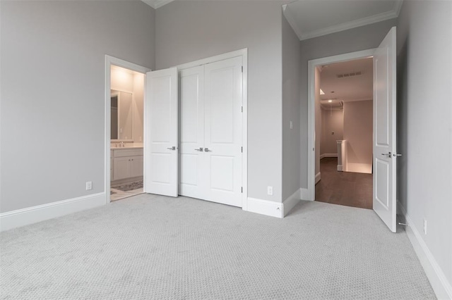 unfurnished bedroom with sink, crown molding, ensuite bath, light colored carpet, and a closet