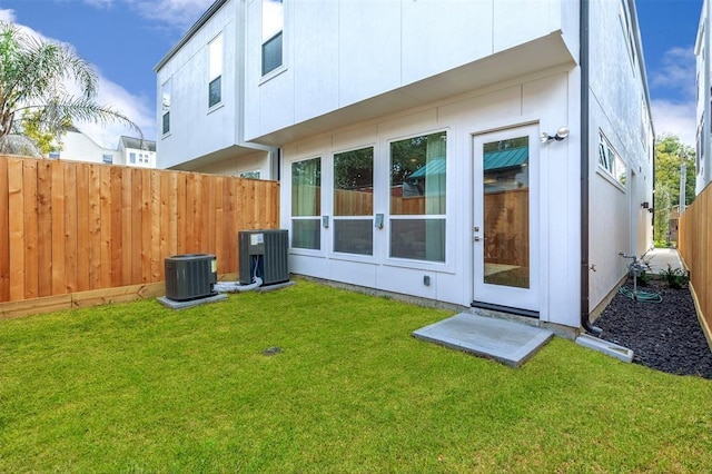 back of house featuring a yard and central AC