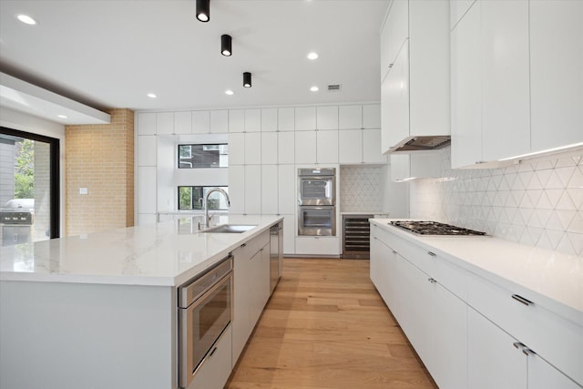 kitchen with white cabinetry, sink, backsplash, and a spacious island