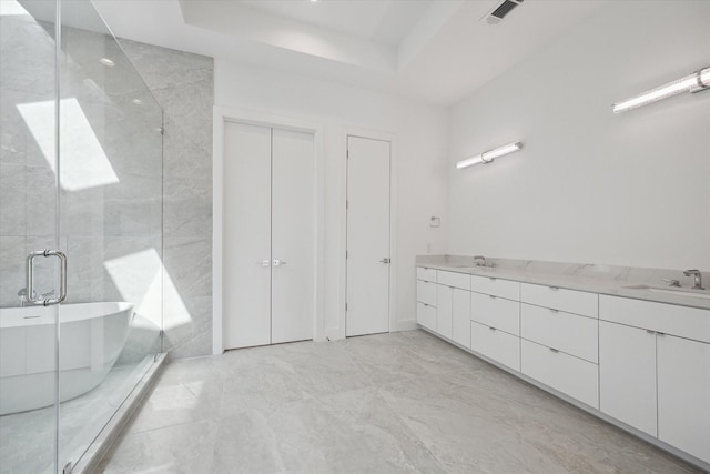 bathroom featuring vanity, a raised ceiling, and independent shower and bath