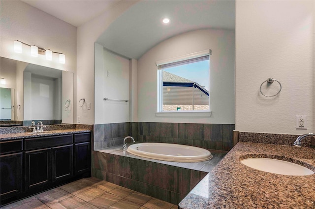 bathroom with tile patterned flooring, vanity, and tiled bath