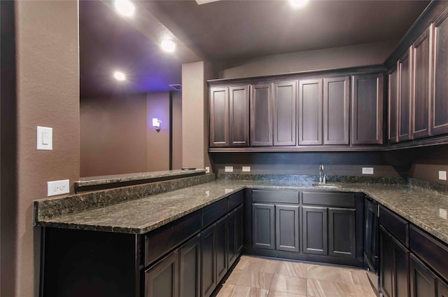 kitchen featuring dark brown cabinets, sink, and dark stone counters