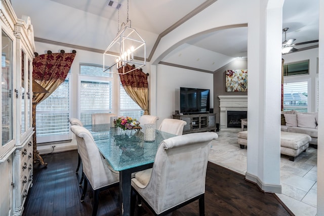 dining space featuring dark hardwood / wood-style flooring, lofted ceiling, and ceiling fan with notable chandelier