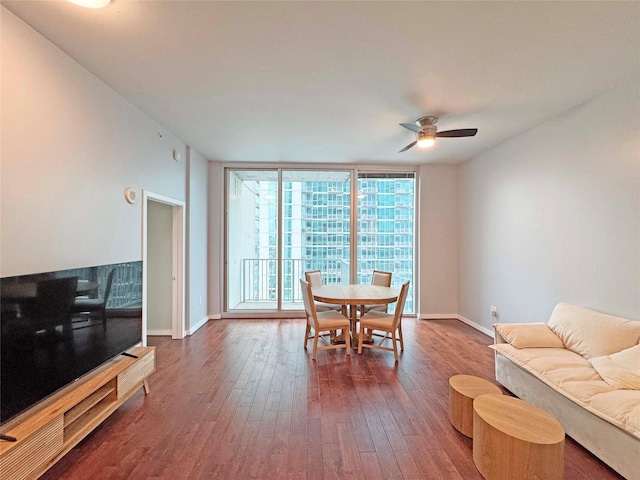 dining space with ceiling fan, dark hardwood / wood-style floors, and a wall of windows