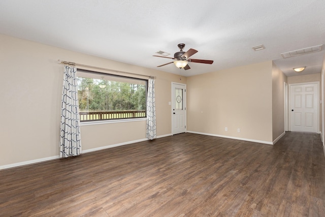 empty room featuring dark wood-style floors, visible vents, baseboards, and ceiling fan