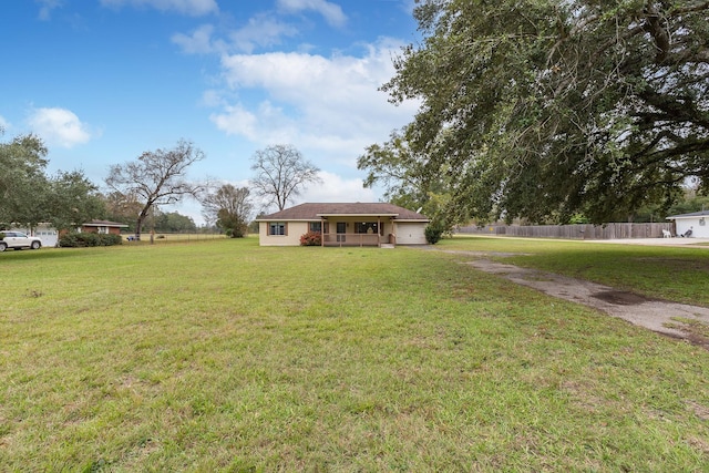 view of yard with driveway, an attached garage, and fence