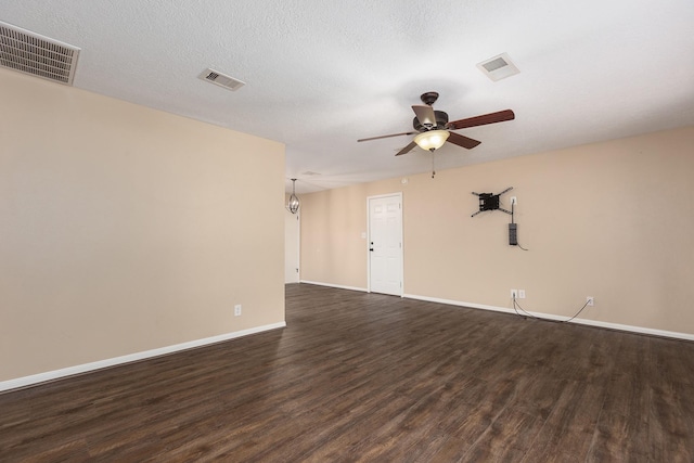 spare room with visible vents, dark wood finished floors, and a ceiling fan