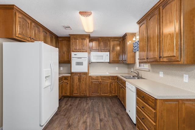 kitchen with brown cabinets, white appliances, light countertops, and a sink