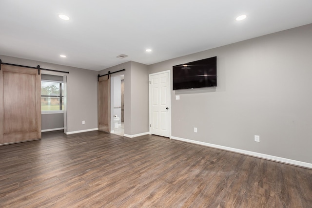 interior space with a barn door, visible vents, baseboards, dark wood-style floors, and recessed lighting