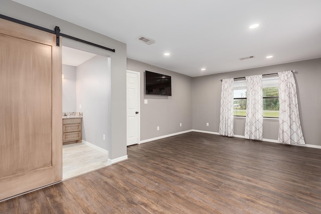 spare room featuring a barn door, wood finished floors, and visible vents