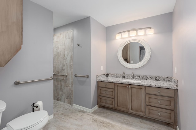 bathroom featuring toilet, baseboards, walk in shower, and vanity